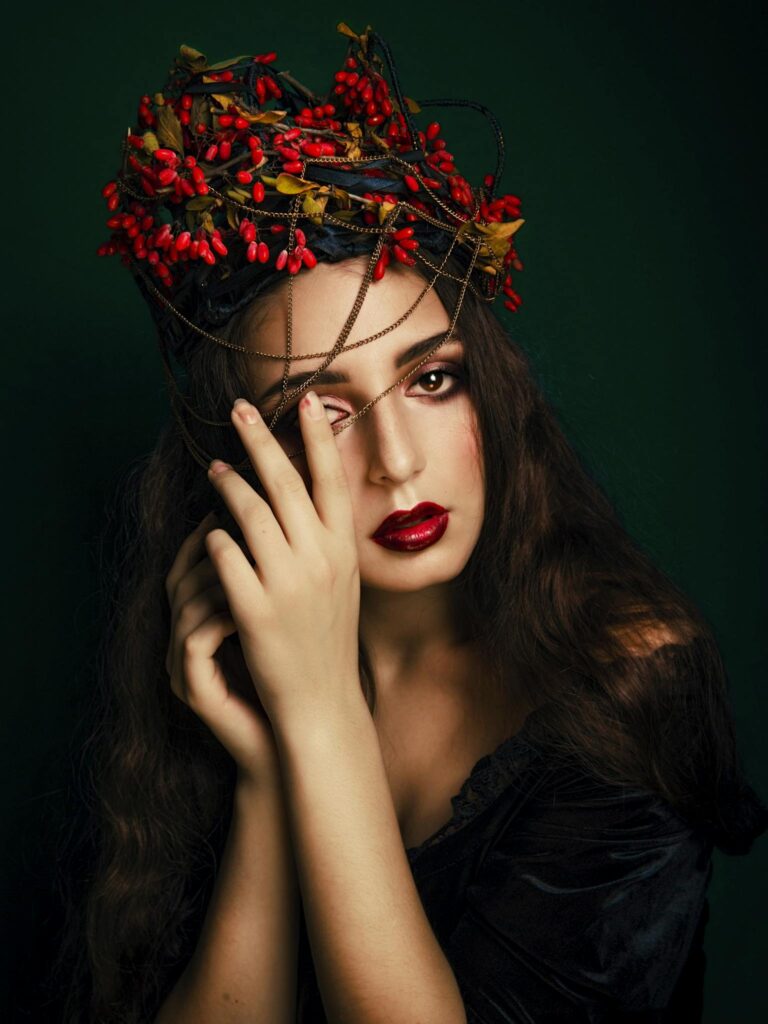 A striking portrait of a woman with an artistic red headdress, embodying elegance and mystery.