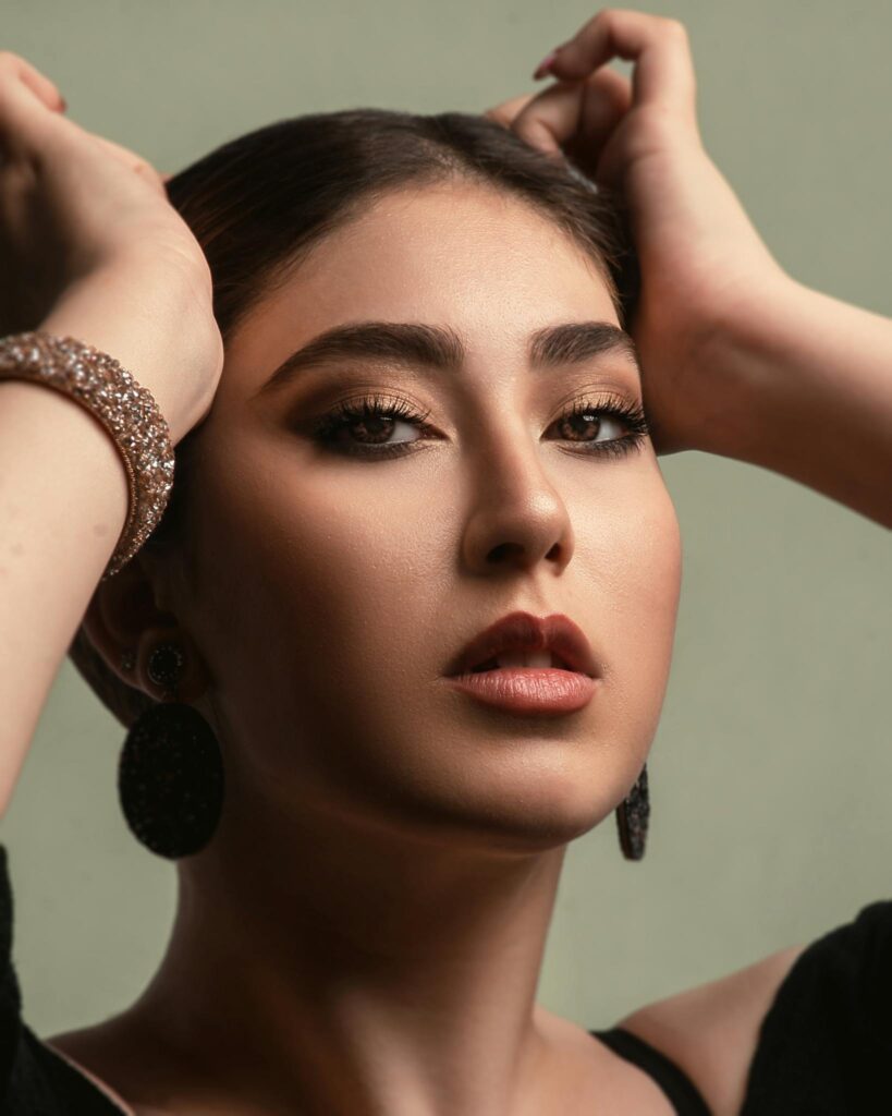 Close-up portrait of a young woman posing gracefully in a studio with stylish accessories.