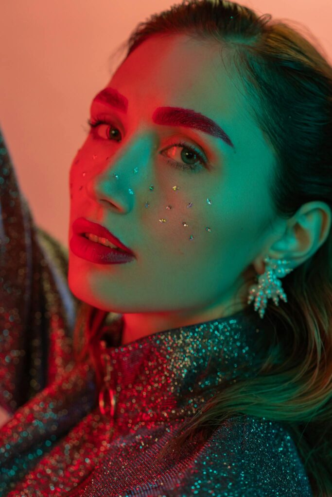 Colorful portrait of woman with glitter makeup and bold fashion style, artistic lighting.